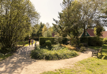 Familie går over bro i grøn park nær Park «Duc de Brabant 3» chalet, Nederlandene, solrig dag.