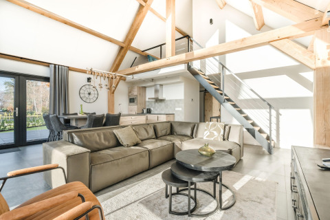 Lyst og moderne opholdsstue i en lodge med synlige bjælker, lædersofa og åben hems i Park de Kievit 22.