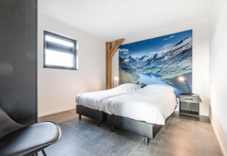 Soveværelse på Park de Kievit 22-lodge i Belgien med to senge og bjerglandskab på væggen.