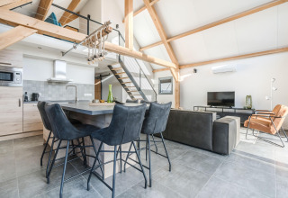Moderne lodgeindretning på Park de Kievit 22 i Belgien med åbent køkken, spisebord og stue