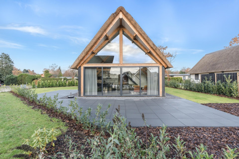 Moderne lodge med stort glasparti og stråtækt tag i Park de Kievit 22, smukke omgivelser i Belgien.
