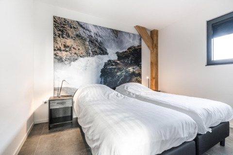 Moderne soveværelse på Park de Kievit 22-lodge i Belgien med to enkeltsenge og naturbillede på væggen.