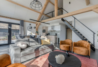 Sala de estar luminosa y moderna en el chalet Park de Kievit 19, Bélgica, con altillo y decoración elegante.