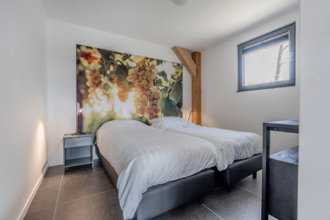 Schlafzimmer im Chalet Park „de Kievit 19“ in Belgien mit zwei Betten und Traubenbild an der Wand.