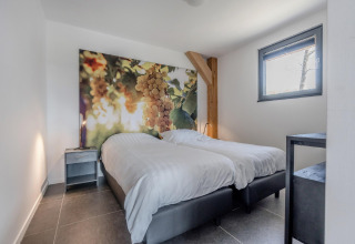 Schlafzimmer im Chalet Park „de Kievit 19“ in Belgien mit zwei Betten und Traubenbild an der Wand.