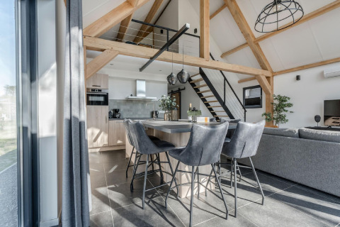 Interior moderno de chalet en Park de Kievit 19 en Bélgica con cocina abierta, comedor y vigas a la vista.