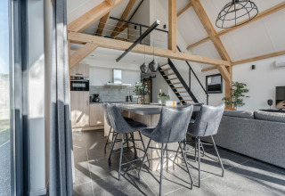 Interior moderno de chalet en Park de Kievit 19 en Bélgica con cocina abierta, comedor y vigas a la vista.