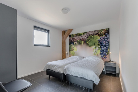 Schlafzimmer im Chalet Park de Kievit 19 in Belgien mit Doppelbett, Traubenbild und modernem Design.