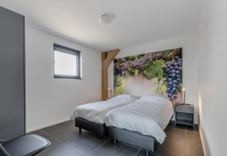 Dormitorio en el chalet Park de Kievit 19 en Bélgica con camas individuales, mural de uvas y decoración moderna.