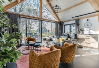 Modernes Chaletinterieur im Park de Kievit 19, Belgien, mit großen Fenstern, stilvollen Möbeln und Naturblick.