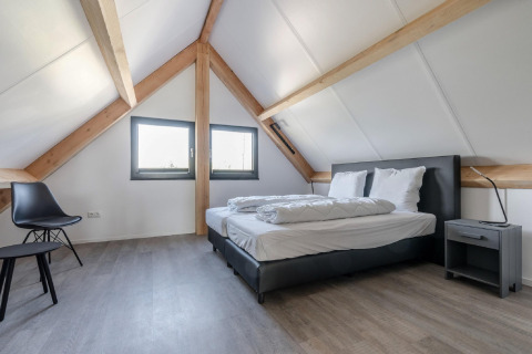 Modernes Schlafzimmer im Chalet Park de Kievit 19 in Belgien mit Holzdecken, Doppelbett und schlichter Einrichtung.