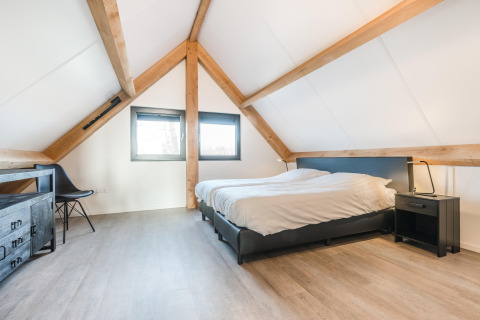 Lyst soveværelse med synlige træbjælker og moderne møbler i Park de Kievit 22, Belgien.