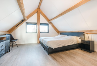Lyst soveværelse med synlige træbjælker og moderne møbler i Park de Kievit 22, Belgien.