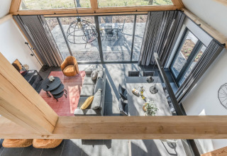 Luftaufnahme eines modernen Wohnzimmers im Chalet Park de Kievit 19, Belgien, mit großen Fenstern und stilvollen Möbeln.