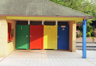 Puertas de baño coloridas en un alojamiento glamping, bajo techo rodeadas de vegetación y naturaleza.