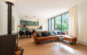 Modern living room at Wellness Suite lodge in the Netherlands with large windows and a brown leather sofa.