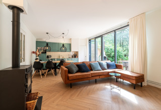 Moderne stue i Wellness Suite-lodge i Holland med lædersofa, stort vindue og åbent køkken.