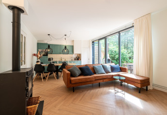 Modern living room at Wellness Suite lodge in the Netherlands with large windows and a brown leather sofa.