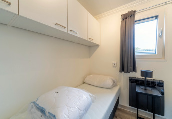 Lille, lyst soveværelse i Brabants Weelde 33 med enkeltseng, skabe, vindue og sort natbord.