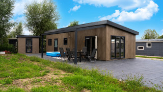 Modern wooden lodge at Brabants Weelde 33 featuring a patio, outdoor dining set, and a small inflatable pool.