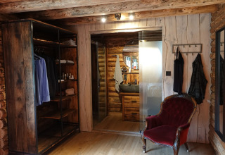 Dormitorio rústico en el chalet Park «de Kievit 11» en Bélgica, con muebles de madera y sillón vintage.