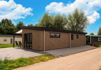 Moderne træbeklædt lodge ved Brabants Weelde 33 i Holland med stor terrasse og grøn omgivelse.