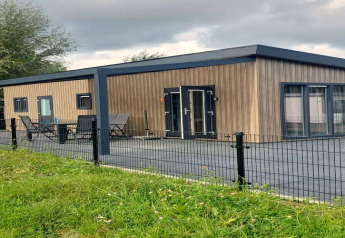 Moderne lodge ved navn Brabants Weelde 33 i Holland, med træbeklædning, terrasse og metalhegn.