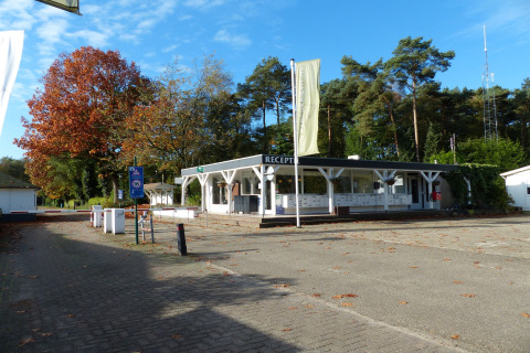 Reception på Park de Kievit 11, Belgien, omgivet af træer og blå himmel på en solrig dag.