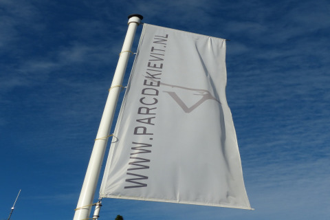 Foto de una bandera con WWW.PARCDEKIEVIT.NL sobre el cielo azul, tomada en el chalet Park de Kievit 11 en Bélgica.