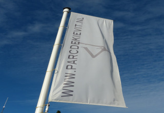 Foto de una bandera con WWW.PARCDEKIEVIT.NL sobre el cielo azul, tomada en el chalet Park de Kievit 11 en Bélgica.