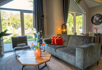 Moderne stue i Holiday Park «Latour 4», Nederlandene, med store vinduer og udsigt til naturen.