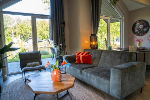 Modern living room at Holiday Park «Latour 4» in the Netherlands with large windows and garden view.
