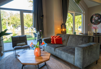 Sala moderna en Holiday Park «Latour 4» en los Países Bajos con grandes ventanas y vista al jardín.