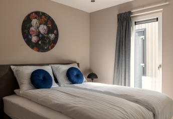 Moderne soveværelse i Holiday Park «Latour 4» i Holland med dobbeltseng, kunst og naturligt lys.