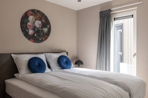 Modern bedroom in Holiday Park «Latour 4» in the Netherlands, with double bed, round art, and sunlight.