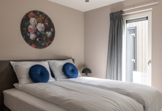 Moderne soveværelse i Holiday Park «Latour 4» i Holland med dobbeltseng, kunst og naturligt lys.