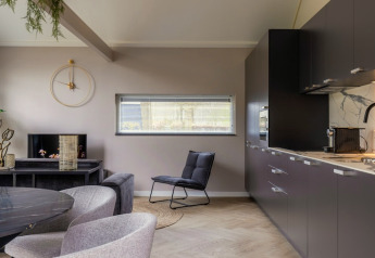 Moderne stue og køkken i Holiday Park «Latour 4» i Holland med minimalistisk indretning og grå toner.