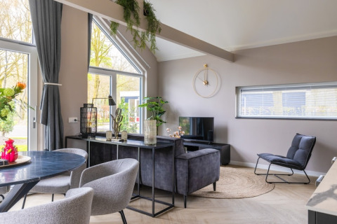Moderne stue i Holiday Park «Latour 4» i Holland med lyse nuancer, komfortable møbler og store vinduer.