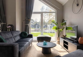Stilfuld stue med store vinduer, udsigt til sø og springvand i Holiday Park Latour 4, Holland.