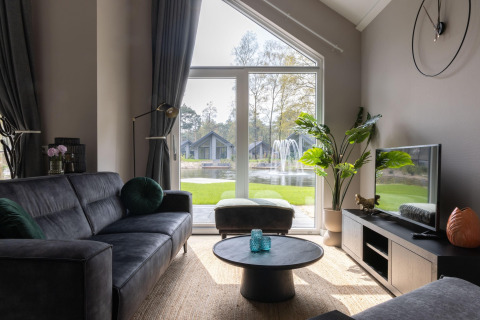 Stilfuld stue med store vinduer, udsigt til sø og springvand i Holiday Park Latour 4, Holland.