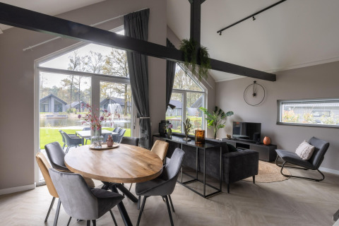 Salon et salle à manger modernes avec grandes fenêtres, vue sur le jardin et le lac au Holiday Park Latour 4, Pays-Bas.