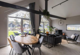 Modern living and dining area with large windows, garden and lake views at Holiday Park Latour 4, Netherlands.