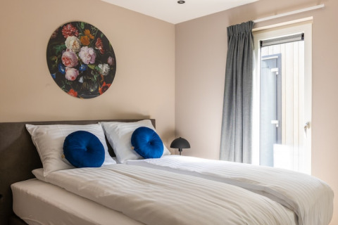Chambre au Holiday Park «Latour 4» aux Pays-Bas, lit double, coussins bleus et décoration florale murale.