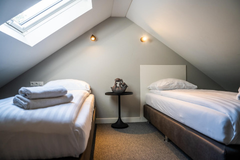 Chambre mansardée avec deux lits simples et une fenêtre de toit chez Holiday Park Latour 4, aux Pays-Bas.