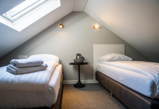 Chambre mansardée avec deux lits simples et une fenêtre de toit chez Holiday Park Latour 4, aux Pays-Bas.