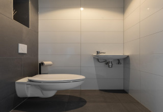 Modern minimalist bathroom with wall-mounted toilet and small sink at Holiday Park Latour 4, Netherlands.