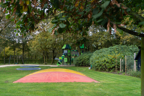 Aire de jeux au Holiday Park Latour 4, Pays-Bas, avec balançoires, toboggan et verdure tout autour.