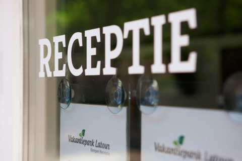 Entrée de la réception avec l'inscription 'RECEPTIE' sur la porte vitrée du Vakantiepark Latour.