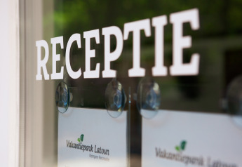 Eingang zur Rezeption mit dem Schriftzug 'RECEPTIE' auf einer Glastür im Ferienpark Latour.