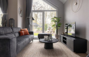 Moderne stue i Holiday Park «Latour 6» i Holland med stor glasdør, sofa og udsigt til natur.